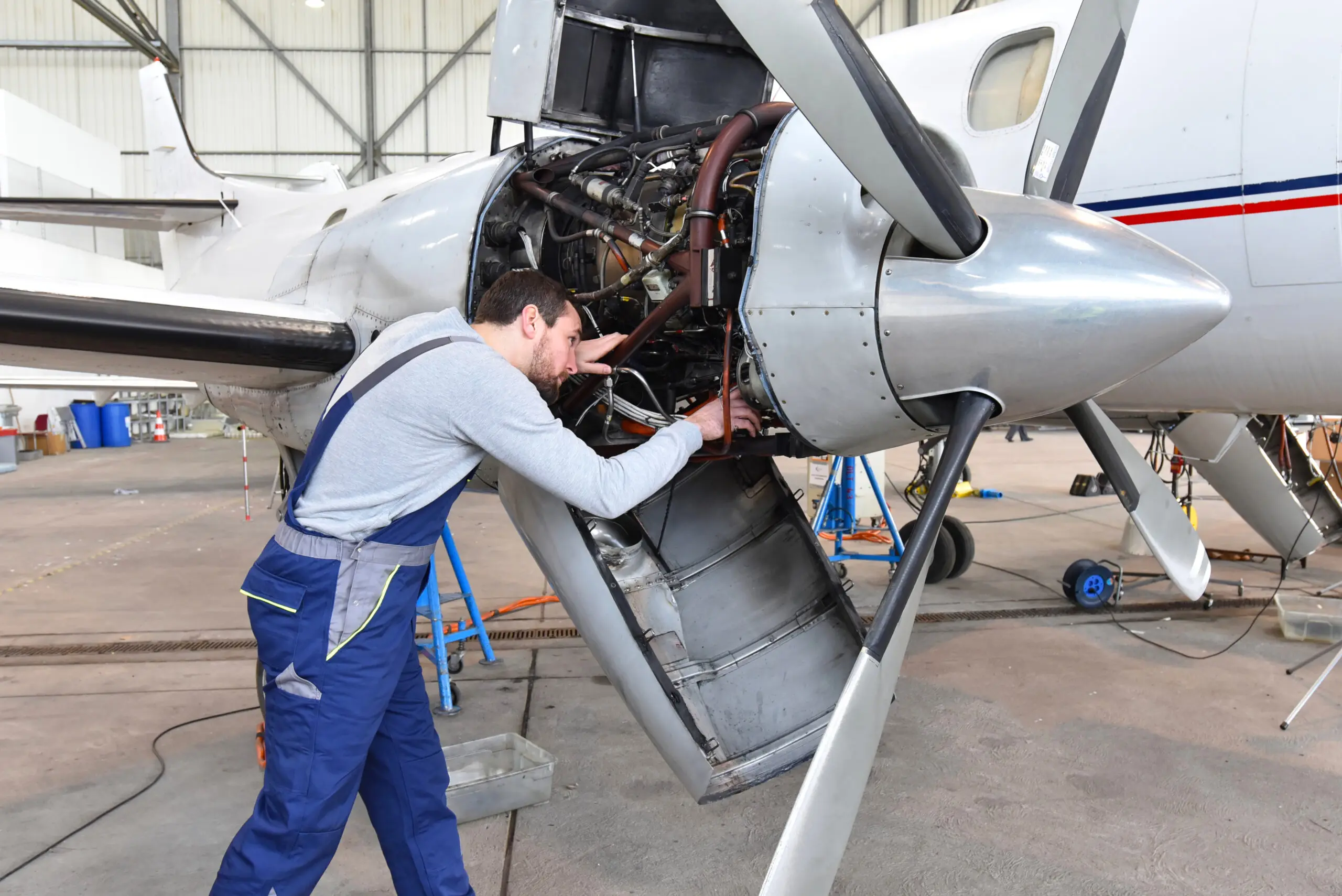 Mechanic inspecting aircraft engine in hangar.