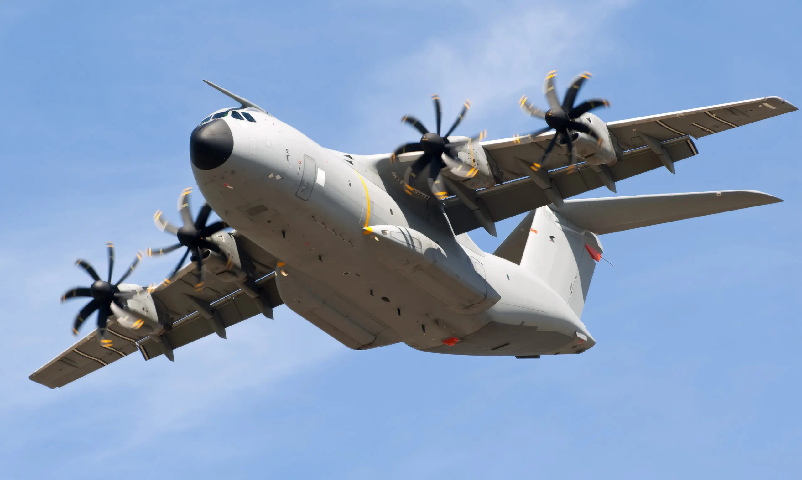 Military transport aircraft flying against blue sky.