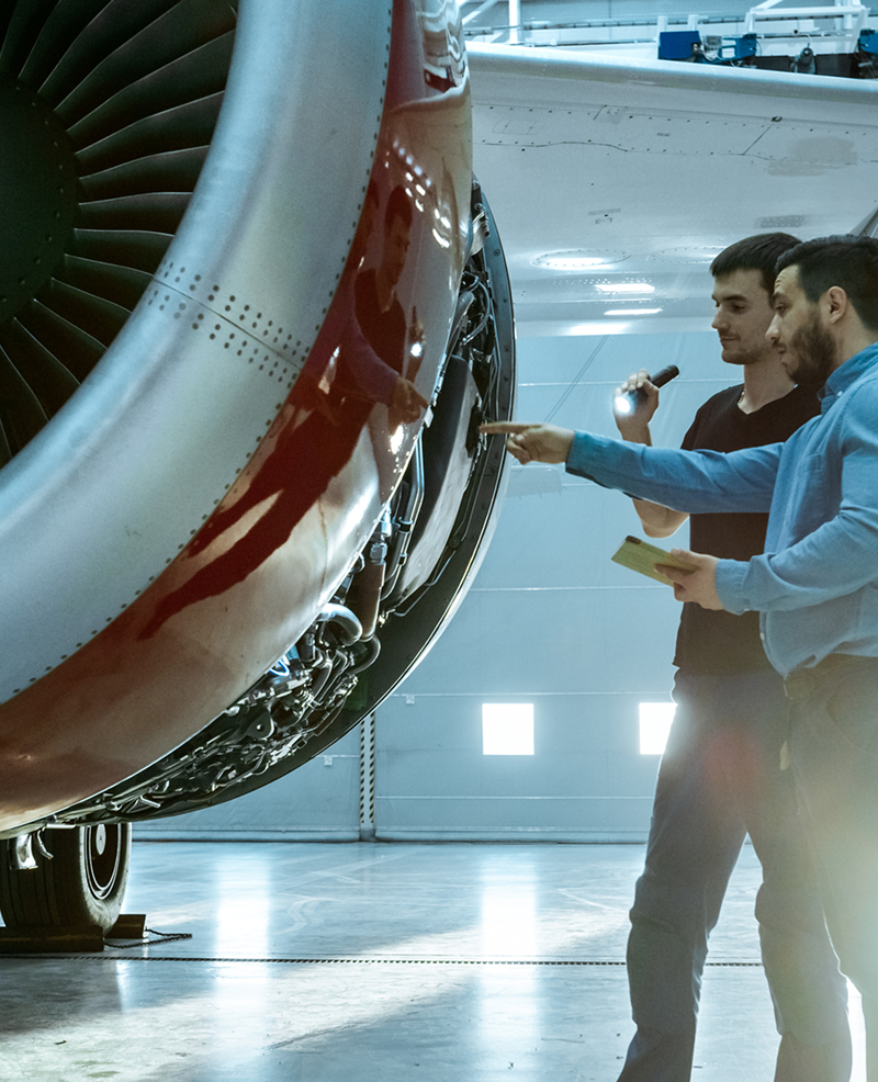 Inspecting aircraft engine in maintenance hangar.